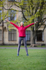 Sports inspired woman standing in park holding her arms up