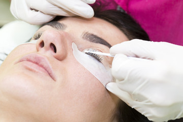 Woman on the procedure for eyelash extensions, eyelashes lamination 