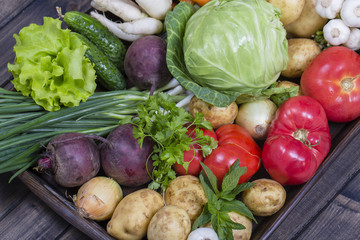 Assortment of fresh vegetables on wooden tray background
