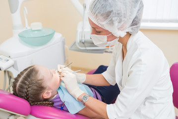 Young girl on a dental exam with female dentists