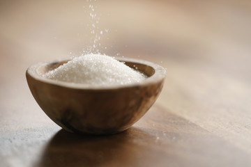 sugar pour in wood bowl on wooden table, with copy space - obrazy, fototapety, plakaty