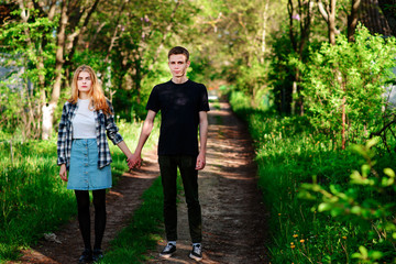 young man holds the hand of his girlfriend, outdoor, standing on the road.