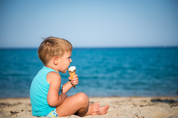 Sweet little child eating ice cream on beach, summertime