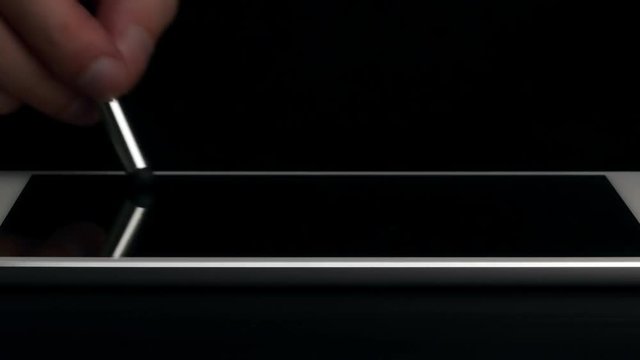 Man draws pictures on electronic tablet with stilus.