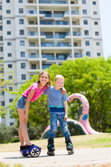 Obraz premium Girl on hoverboard with her brother on rollers having fun outdoors