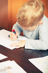 Naklejka premium Kid playing, drawing pictures on paper