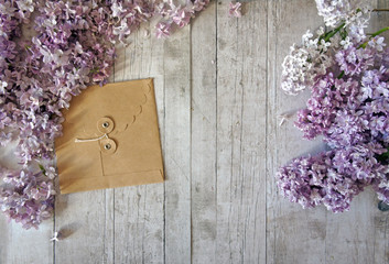 Kraft envelope on a wooden background with lilac branches