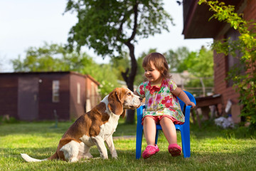 Little girl playing with a dog on the lawn .