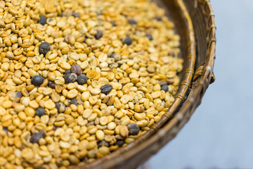 Unprocessed coffee beans put in a basket on a white background.