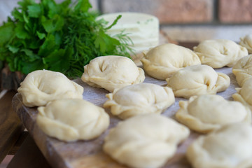 Fototapeta na wymiar Dumplings raw on a wooden board. Russian and Ukraine national food. The process of cooking dumplings.