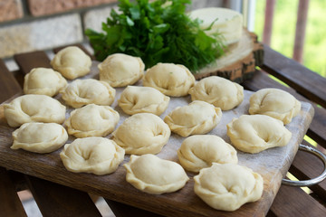 Dumplings raw on a wooden board. Russian and Ukraine national food. The process of cooking dumplings.