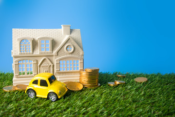home with coin money and yellow car on grass ground