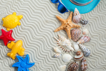 Sea background. Seashells flat still with white sand and child`s clothes on it. traveling