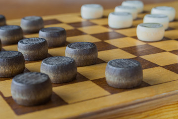 wooden checkerboard with checkers spaced on table (closeup)