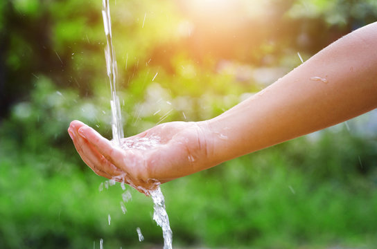 Water pouring splash in hand and nature background