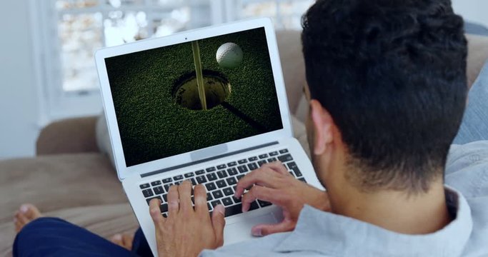Man watching golf on laptop in living room
