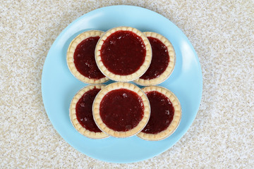 top view strawberry tarts on blue plate