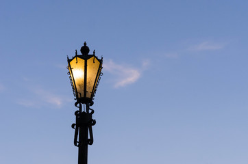 Fototapeta na wymiar Glowing street lamp against a blue sky.