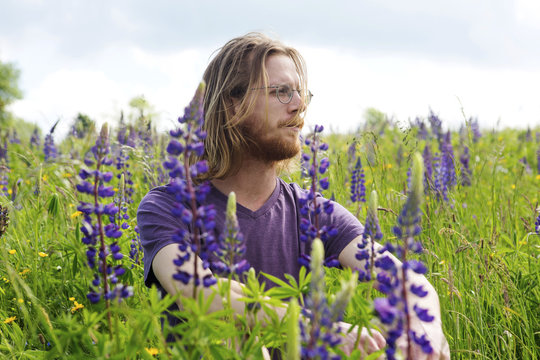 Young Handsome Man Sitting In A Flower Field