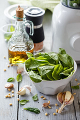 Spinach pesto in a glass jar, decoration: spinach leaves, pine nut, cheese Parmesan, garlic, olive oil.