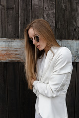 The sexy girl in white trousers about wooden wall