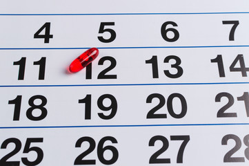 Obraz premium Red pill on the calendar. Schedule medication