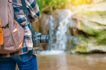 close up of camera with  woman tourist on the background of waterfall