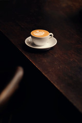Coffee machiato with latte art on wooden table. Dark food photography