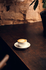 Coffee machiato with latte art on wooden table. Dark food photography