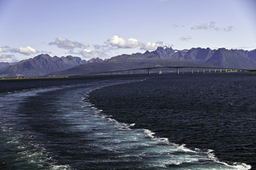 Ship wake from Risoyhamn Bridge, Risoyhamn, Norway, with mountains behind