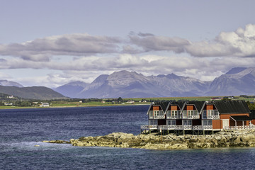 Shoreside home at entrance to Stokemarknes, Norway, with mountains in rear