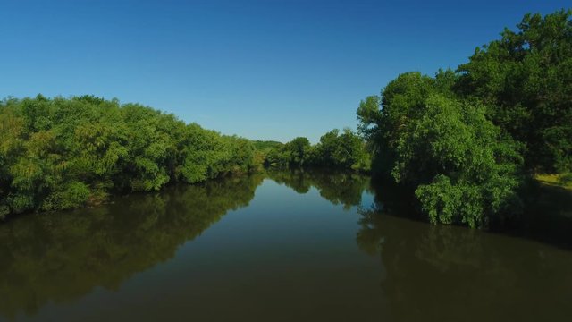 Aerial video of a quiet river and blue sky reflecting in it 