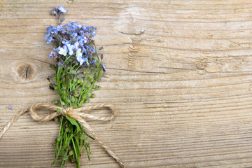 Forget me nots flowers with ribbon on a dark wooden background, copy space
