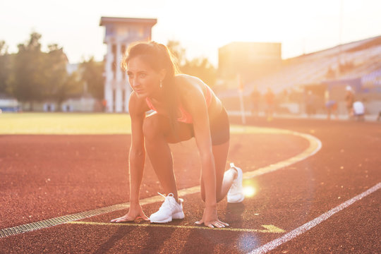 Woman in starting position ready for running in stadium.