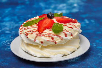 White creamy round cake with strawberries and mint on plate