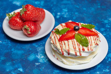 White creamy round cake with strawberries and mint on plate