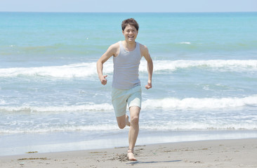 Fototapeta na wymiar ビーチを走る若い男性