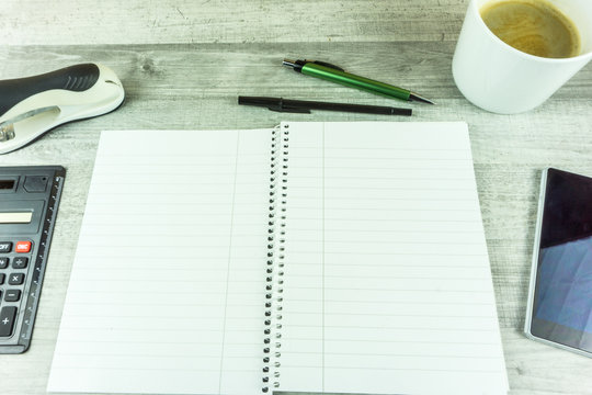 Notebook with coffee, pen and cell phone on a desk