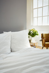 white bed linen fresh flowers on night stand industrial loft