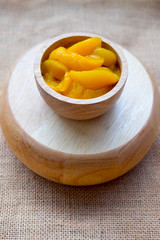 Canned peach slices in wood bowl
