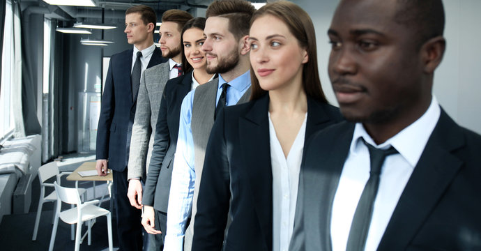 Happy smiling business team standing in a row at office.