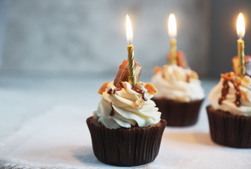 Homemade chocolate  cupcake with nuts and vanilla frosting on wooden board and dark stone background, selective focus. Delicious dessert  for birthday, festive seasons,  engagement or valentine day