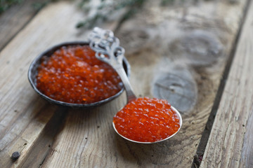 red caviar with bread, butter and herbs on vintage board and wooden background. Sandwich with red caviar