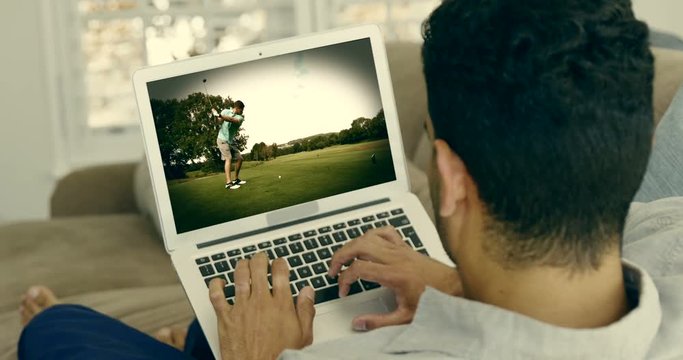 Man watching golf on laptop in living room
