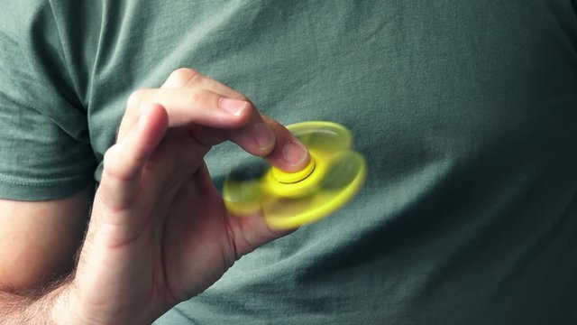Yellow fidget spinner in male hand, selective focus