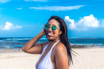 Colorful portrait of young attractive asian woman in sexy white dress on the tropical beach of Bali island, Indonesia.