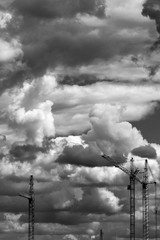 Black and white photos of building cranes against the background of clouds
