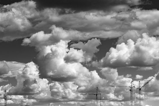 Black and white photos of building cranes against the background of clouds