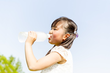 青空バックにペットボトルの水を飲む少女