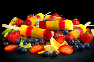 Healthy refreshing fruit popsicle lollies with orange, lime, strawberries, blueberries.